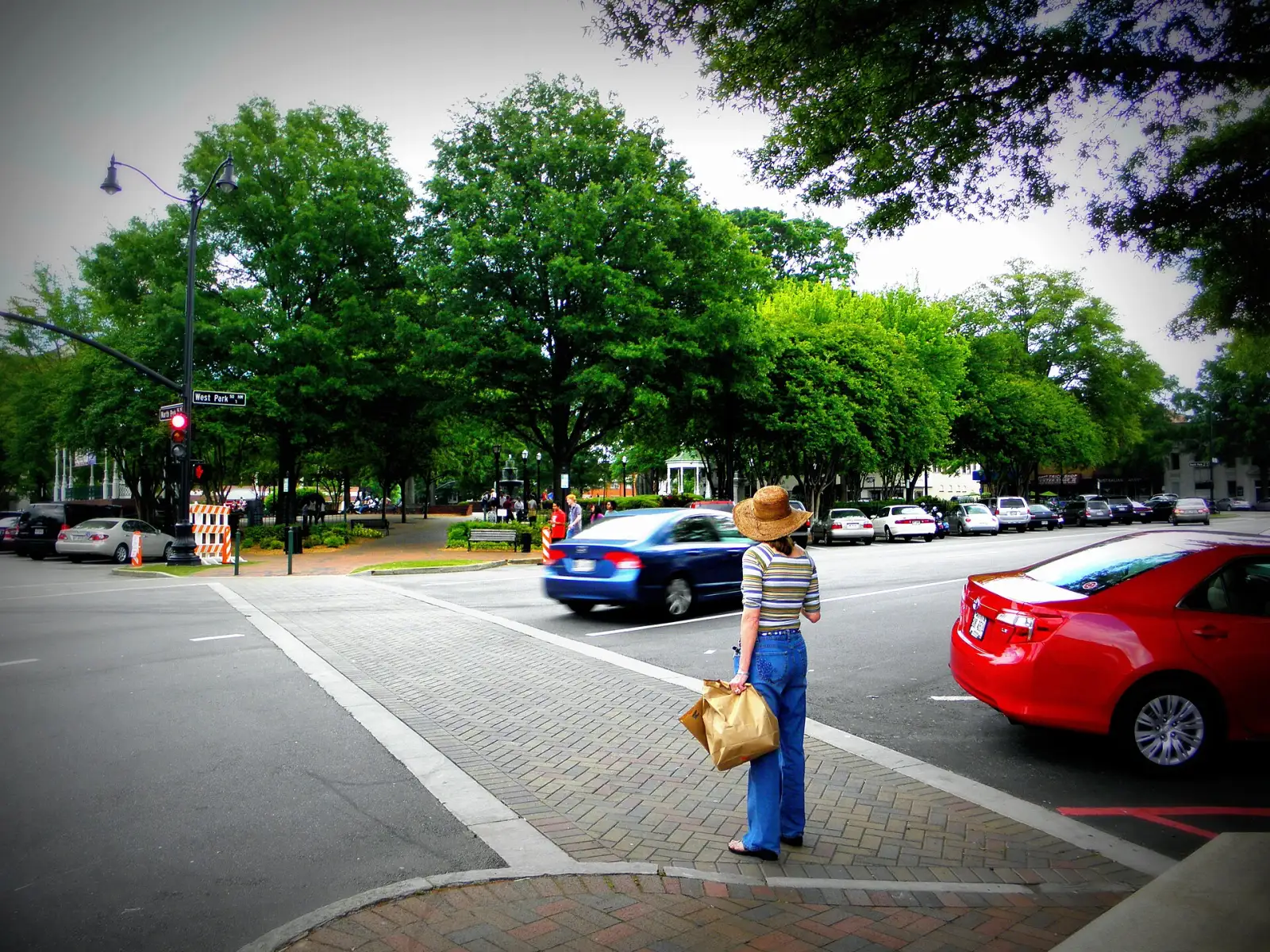 A shopper with a bag waits to cross West Park Square toward Glover Park on Marietta Square