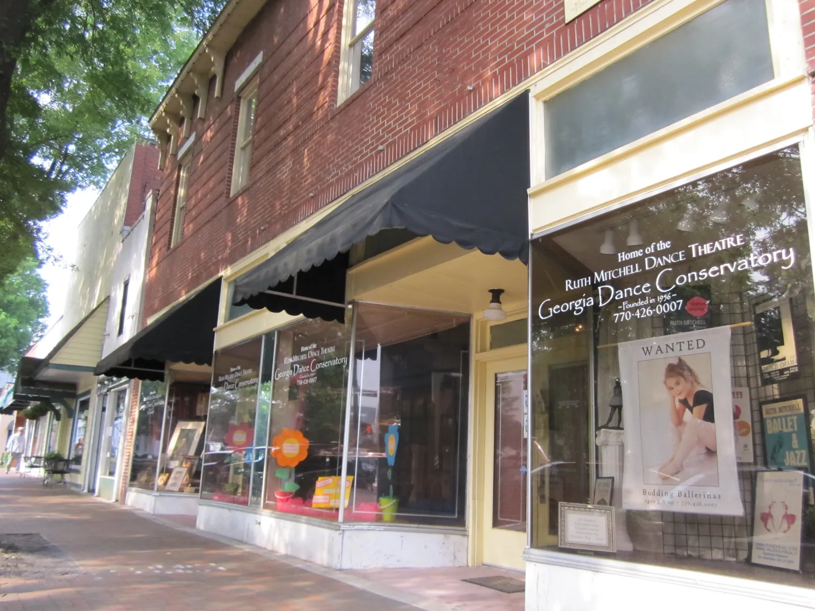 Brick storefronts with awnings along the sidewalk on Marietta Square, where the Dashing Through the Square 5K passes the shops.