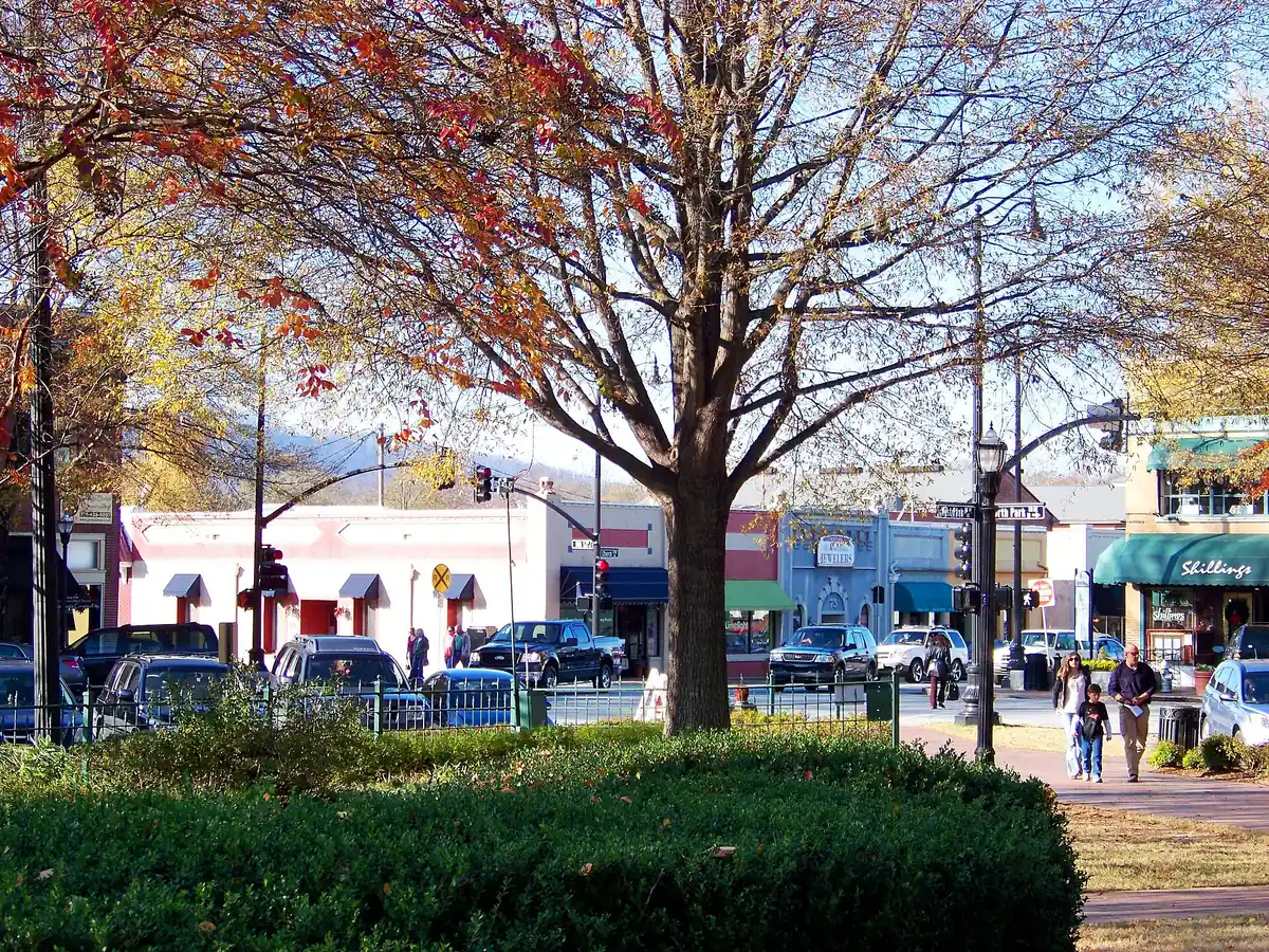 Families walk through Glover Park on Marietta Square on a late fall afternoon, with shops facing the Square behind