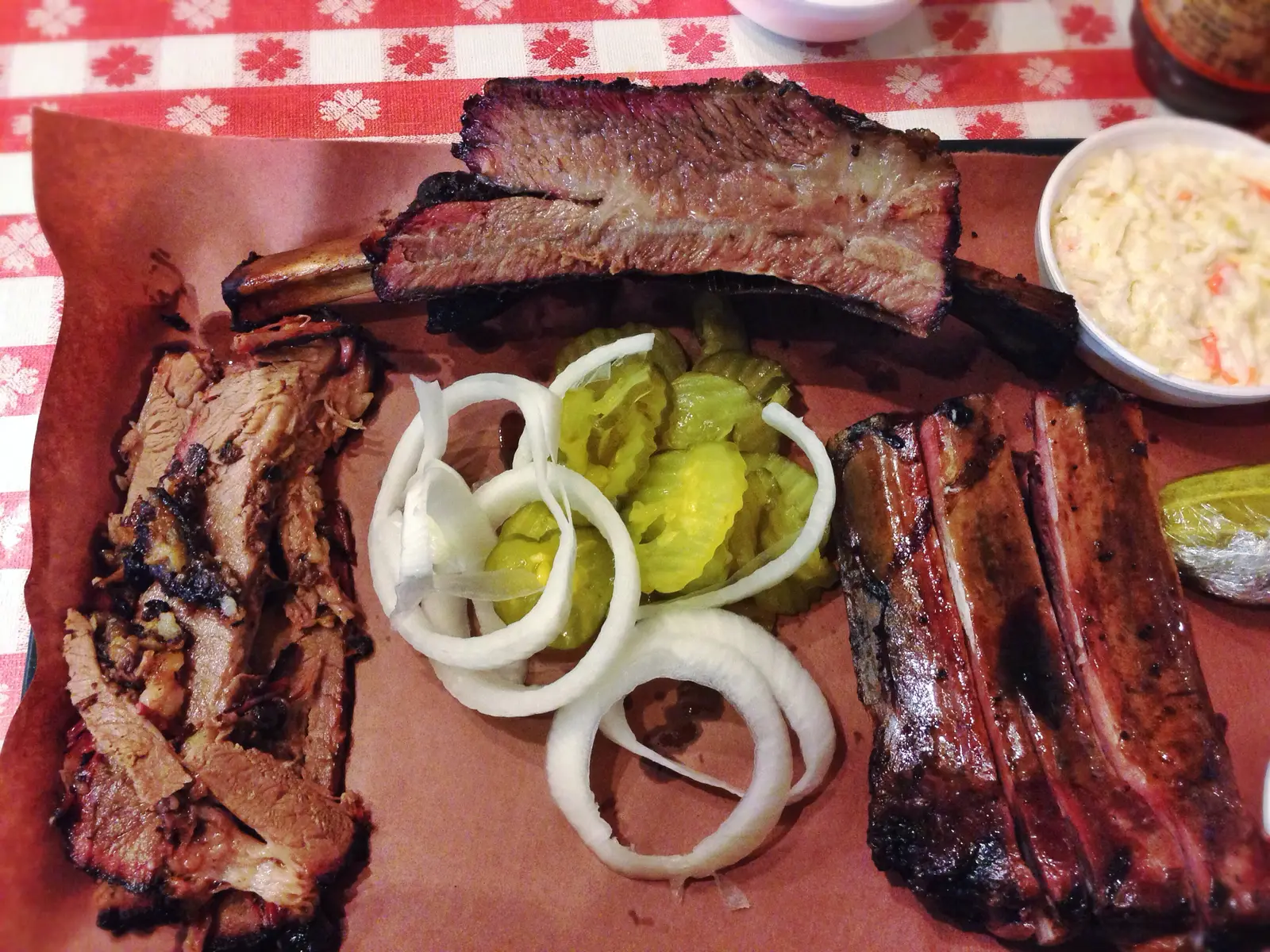 Brisket, beef rib and pork ribs on butcher paper with pickles, onion and slaw. The photo was not taken at a Marietta restaurant.