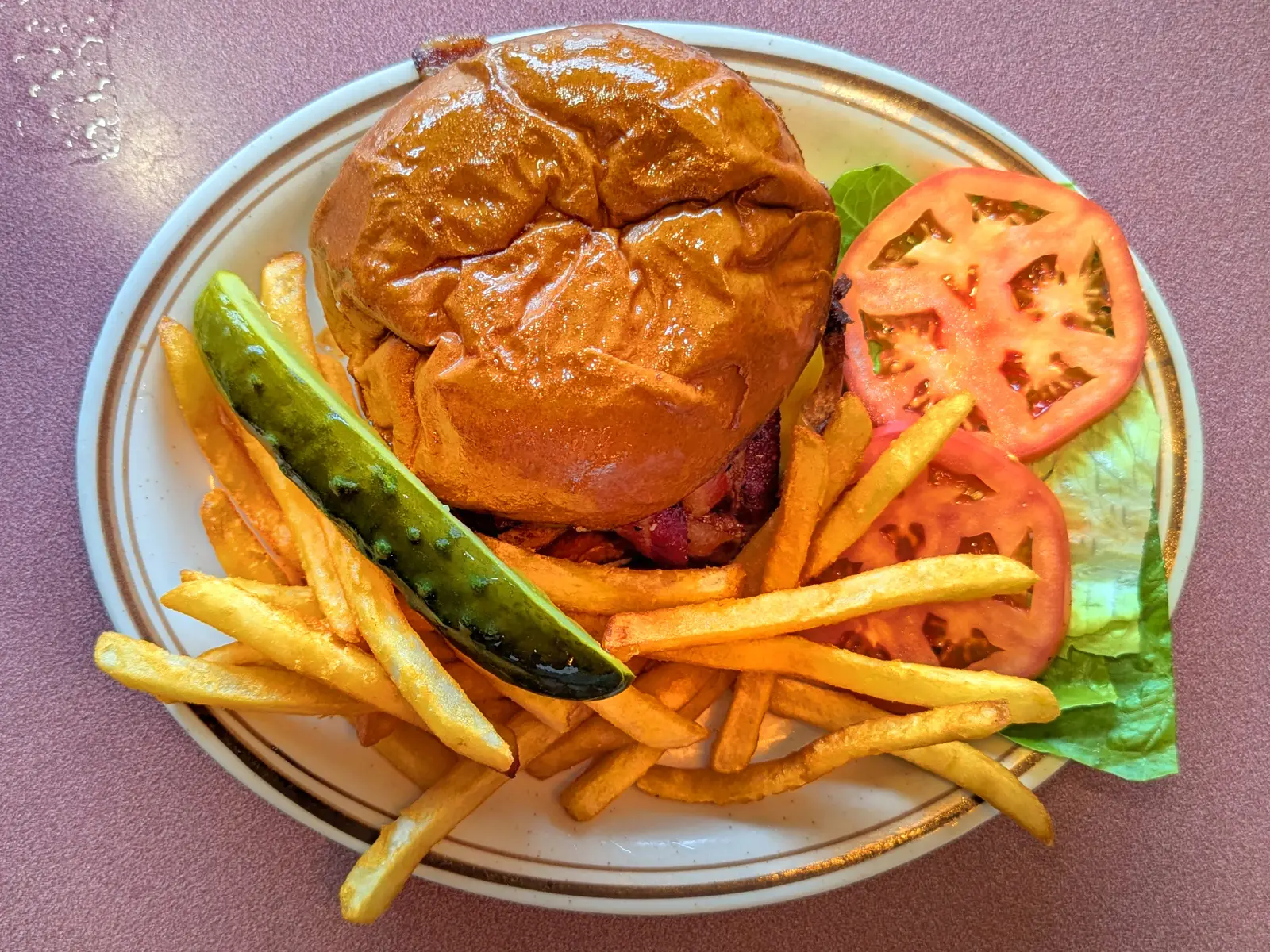 A bacon cheeseburger with French fries, a dill pickle, tomato and lettuce. The photo was not taken at a Marietta restaurant.